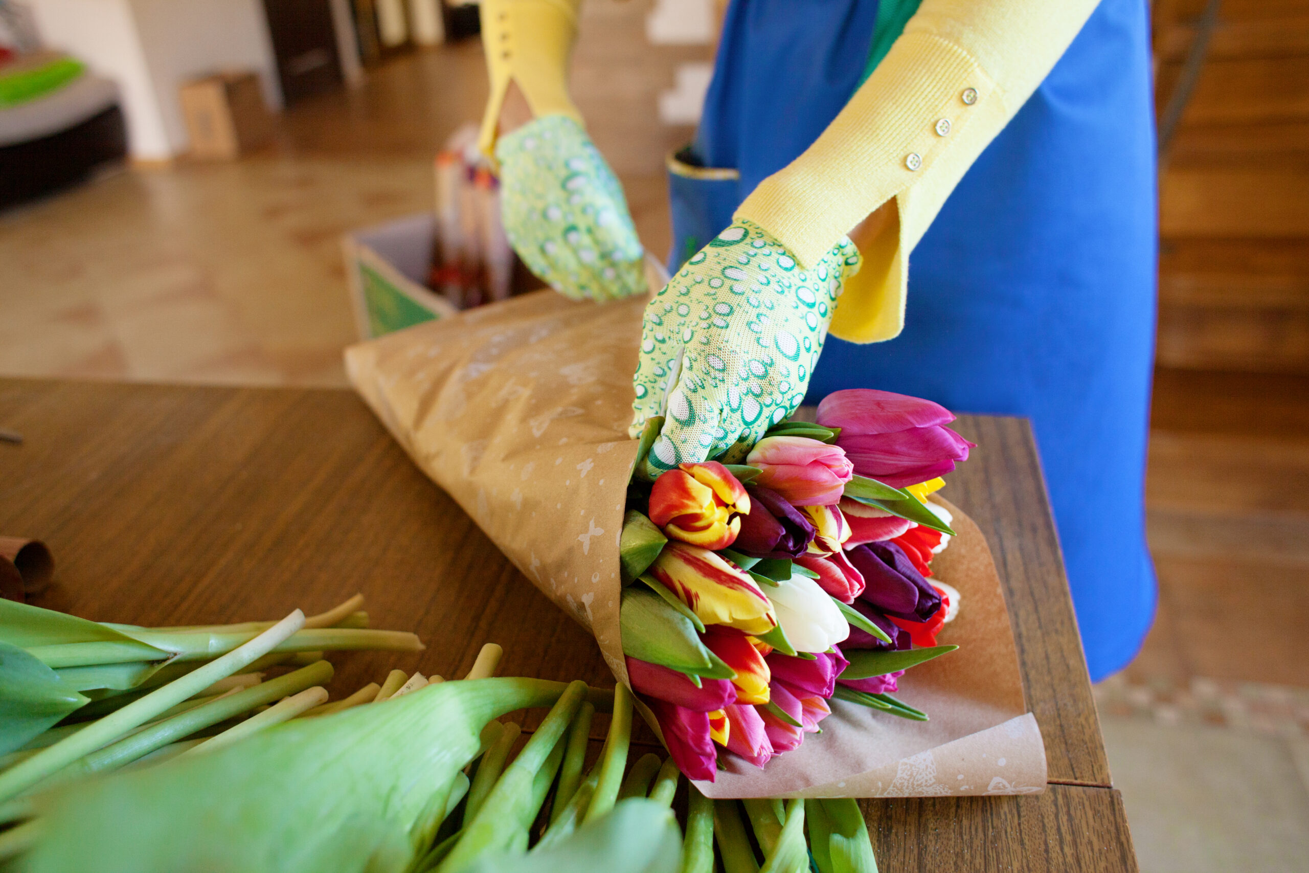 Girl florist is packing beautiful tulips in a flower shop in kraft paper. Women's Day and Valentine's Day